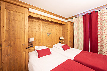 A bedroom with two beds and red curtains
