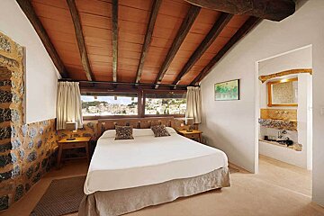 A bedroom with a large bed and a painting on the wall