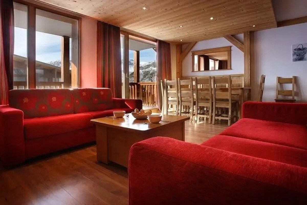 A living room with a red couch , table and chairs