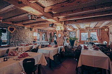 A dining room with tables and chairs and a pot hanging from the ceiling