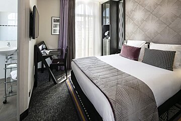 A hotel room with a large bed and a desk