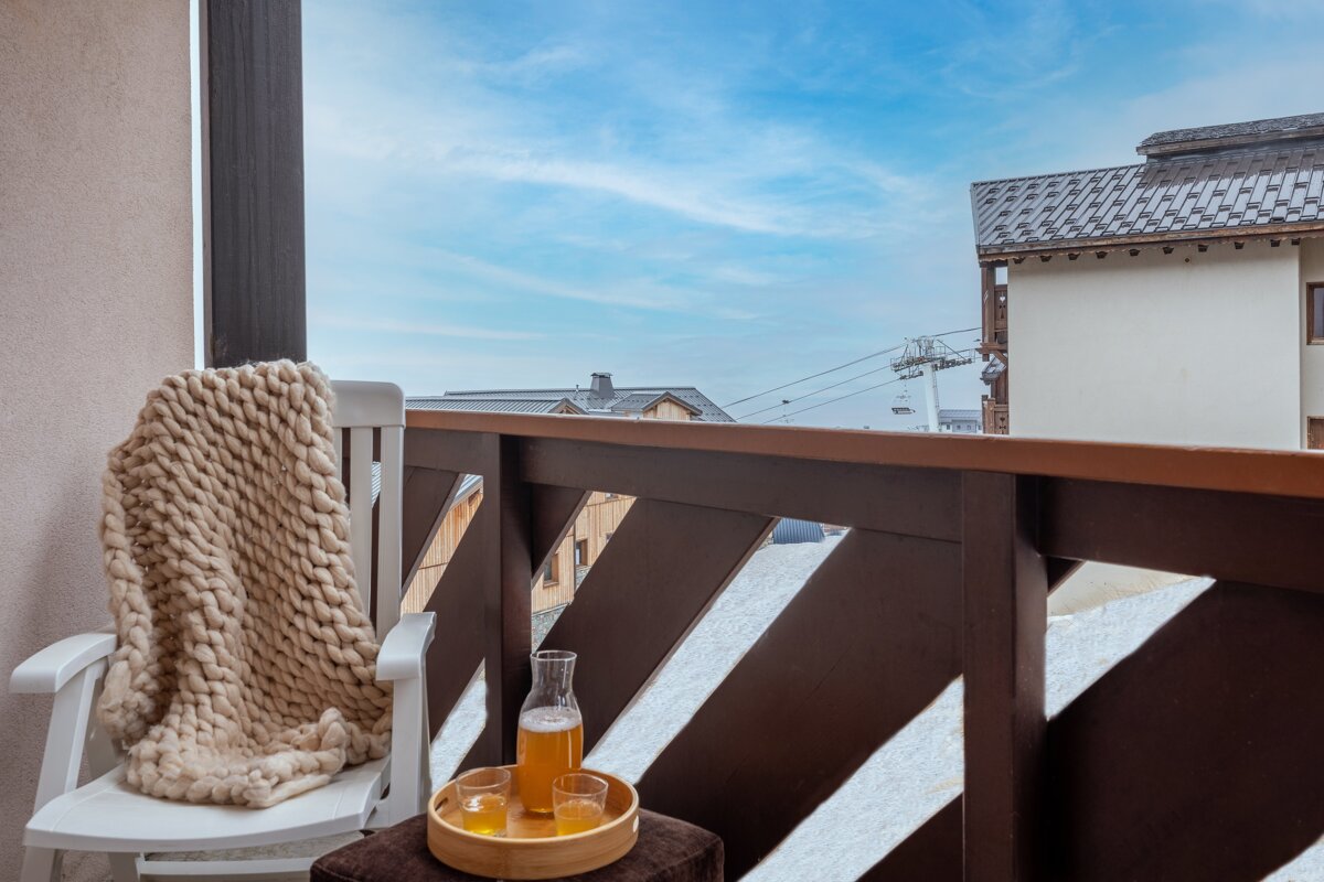 A chair with a blanket on it sits on a balcony