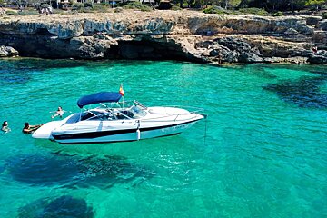 A boat is floating in the water near a rocky shoreline
