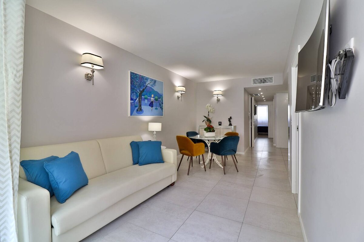A living room with a white couch and blue pillows