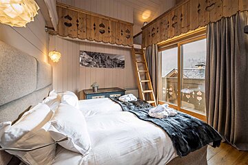 A bedroom with a ladder leading up to a loft