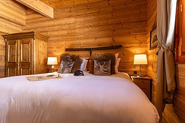 A bedroom in a log cabin with a bed and pillows