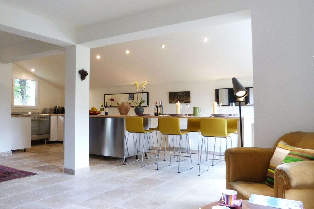 A kitchen with a stainless steel counter and yellow chairs