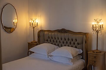 A bedroom with a bed and two lamps and a mirror