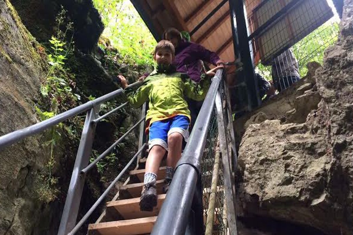 a boy climbing down some steps into a gorge