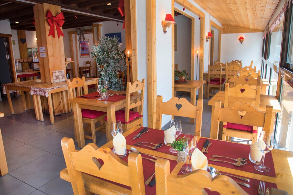 A restaurant with wooden tables and chairs with hearts on them