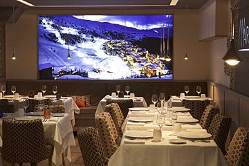 A dining room with tables and chairs and a large picture on the wall