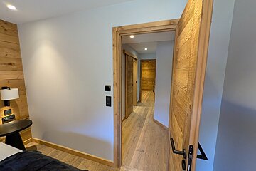 A bedroom with a wooden door that leads to a hallway