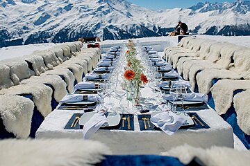 A long table with plates and silverware in front of snowy mountains