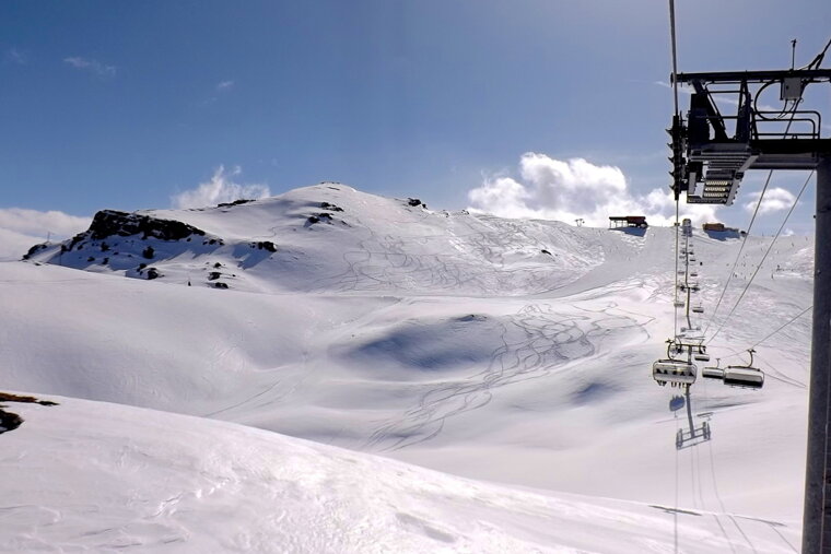 a ski lift passing a vast open area of snow