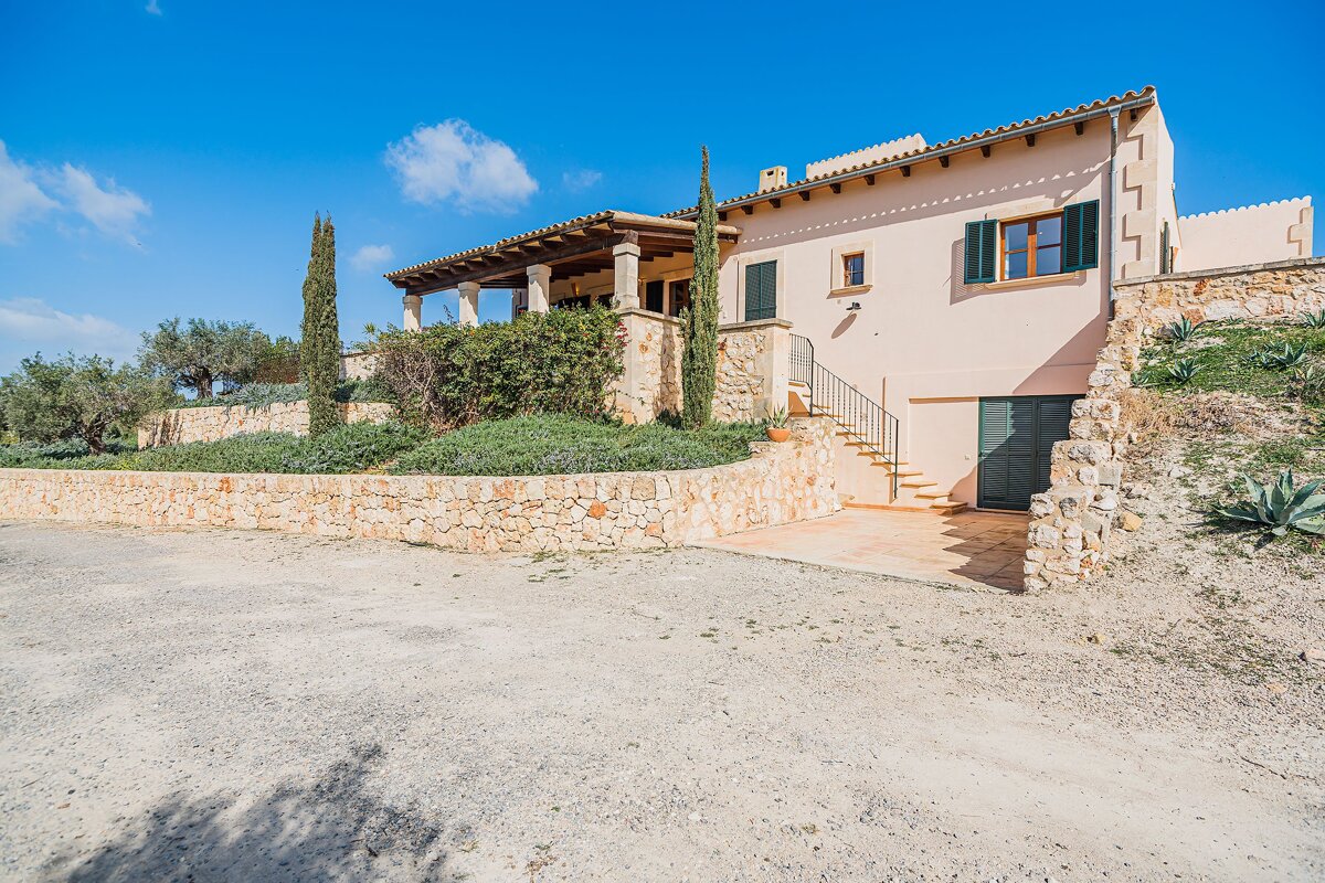 A house with a stone wall and stairs leading up to it