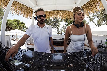 A man and a woman are playing music on pioneer mixers