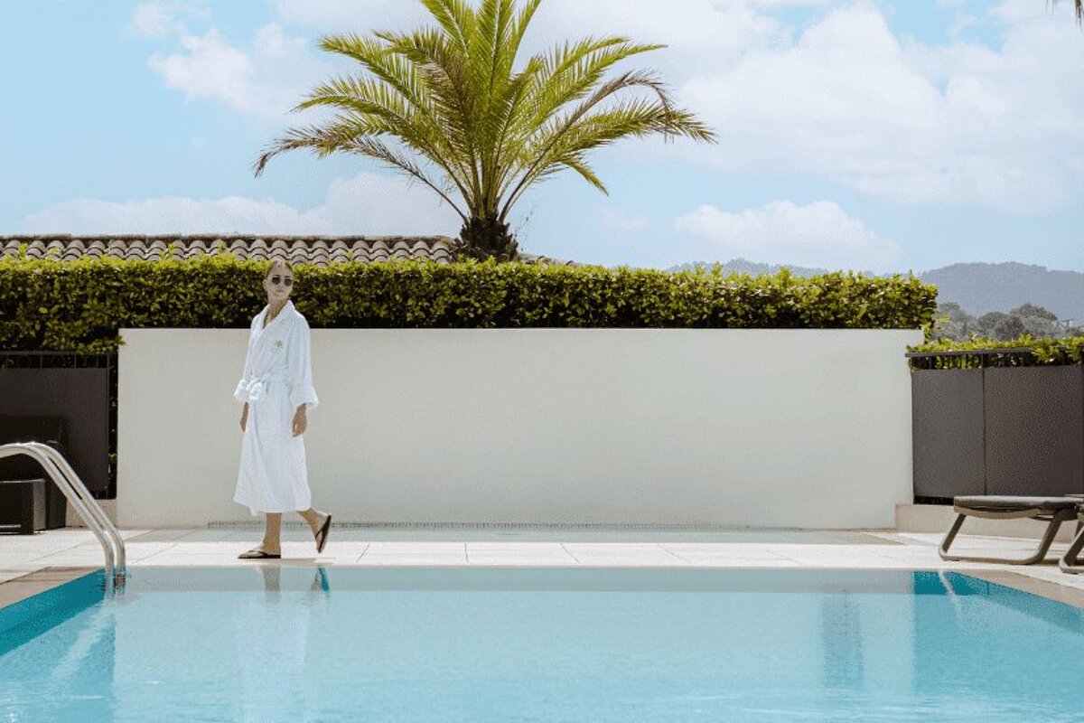 A woman in a bathrobe walks by a swimming pool
