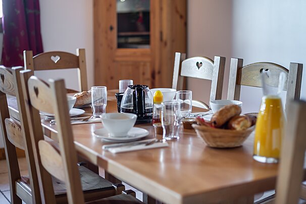 A table with a bowl of bread and a bottle of orange juice on it