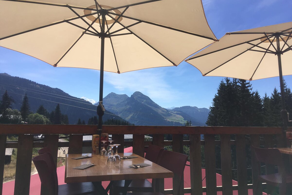 Two umbrellas are sitting on a balcony overlooking mountains