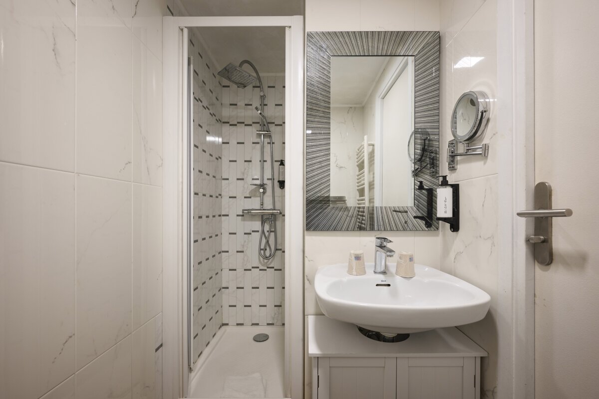 A bathroom with a sink a mirror and a shower