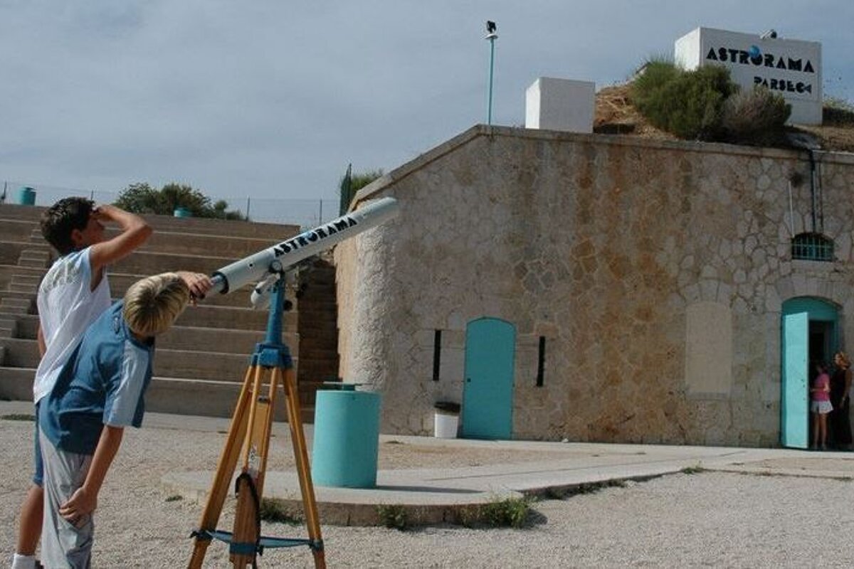 A boy looking through an astrorama telescope in front of a building
