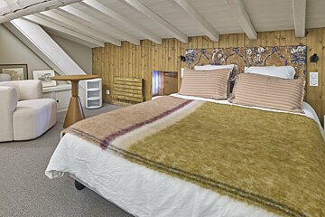 A bedroom with a bed a chair and a table