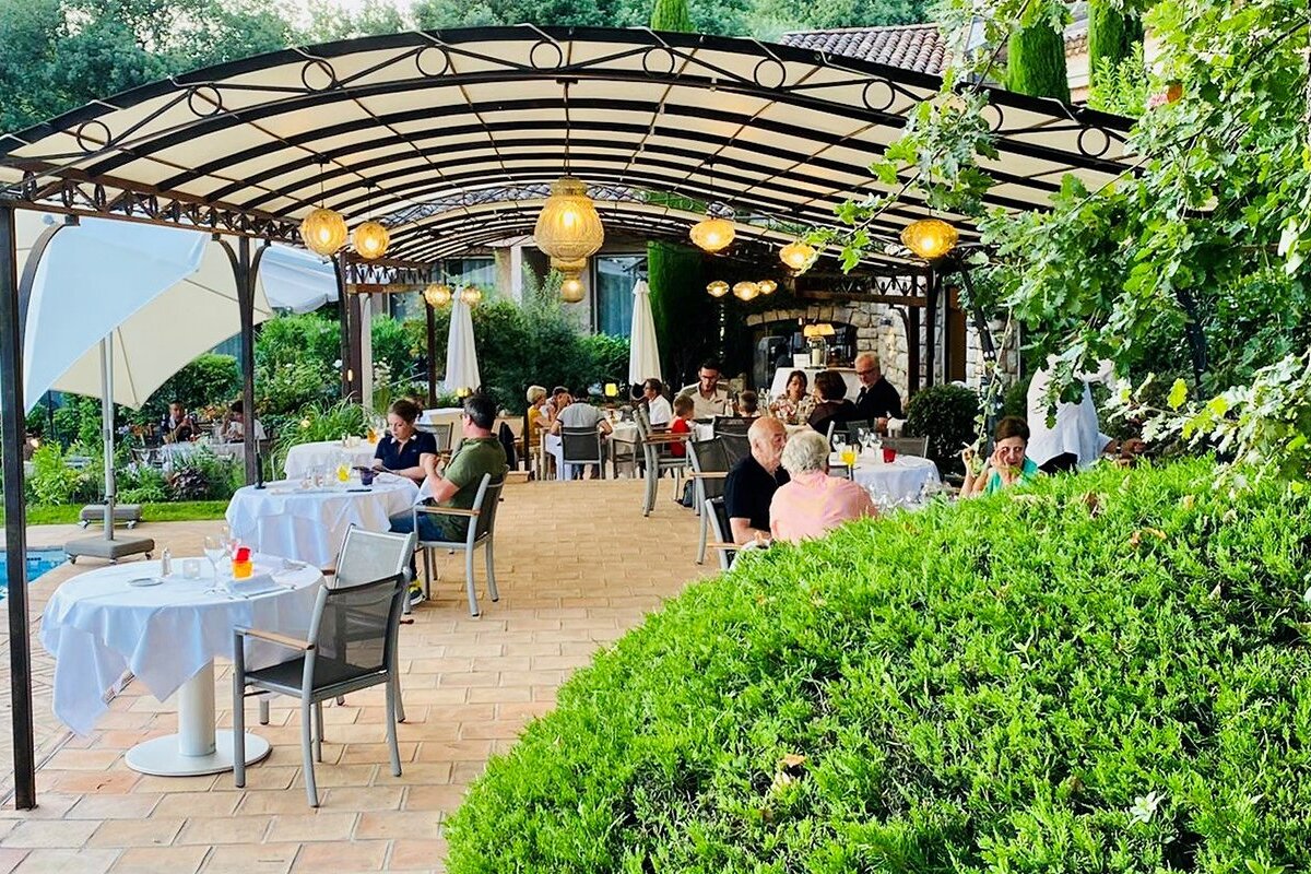 A group of people are sitting at tables under a canopy