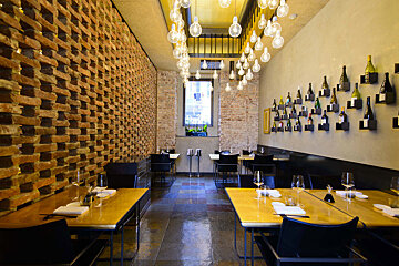 A restaurant with tables and chairs and bottles on the wall