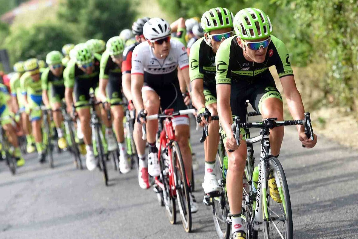 A group of cyclists wearing cannondale uniforms are riding down a road