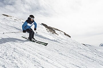 A person skiing down a snowy slope wearing a blue jacket