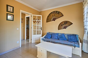 A room with a couch and two fans on the wall
