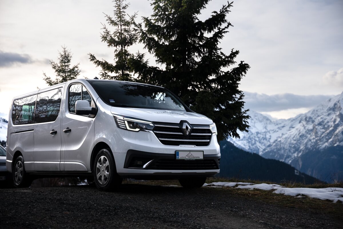 A white van is parked in front of a snowy mountain