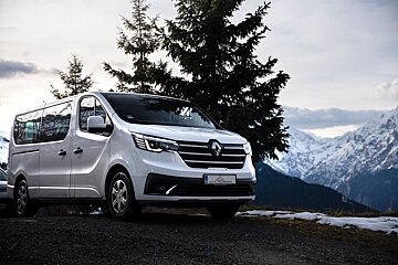 A white van is parked in front of a snowy mountain