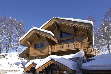A snowy house with a balcony and a blue sky in the background