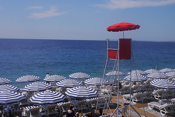 A lifeguard tower with a red umbrella on top of it