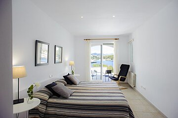 A bedroom with two beds and a balcony overlooking a body of water