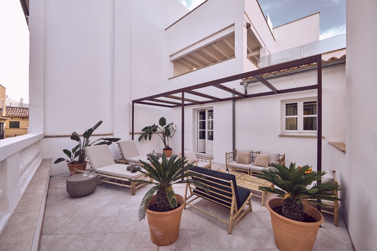 A balcony with furniture and potted plants and a canopy