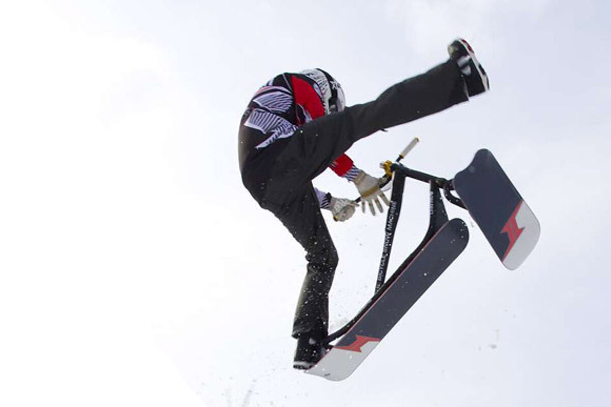 A person is doing a trick on a sled that says ' snowmobile ' on it