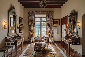 A bathroom with two sinks a chair and two mirrors