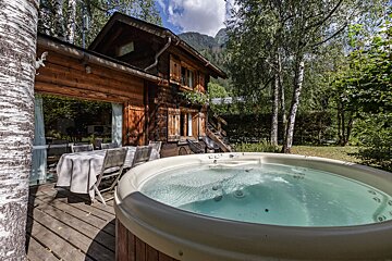 A hot tub sits on a deck in front of a wooden house