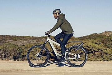 A man wearing a helmet is riding a bike on a dirt road