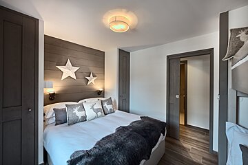 A bedroom with a bed and pillows with deer on them