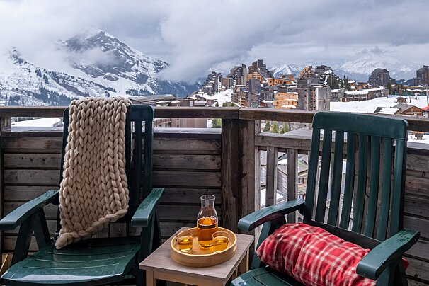 Two chairs on a balcony with mountains in the background