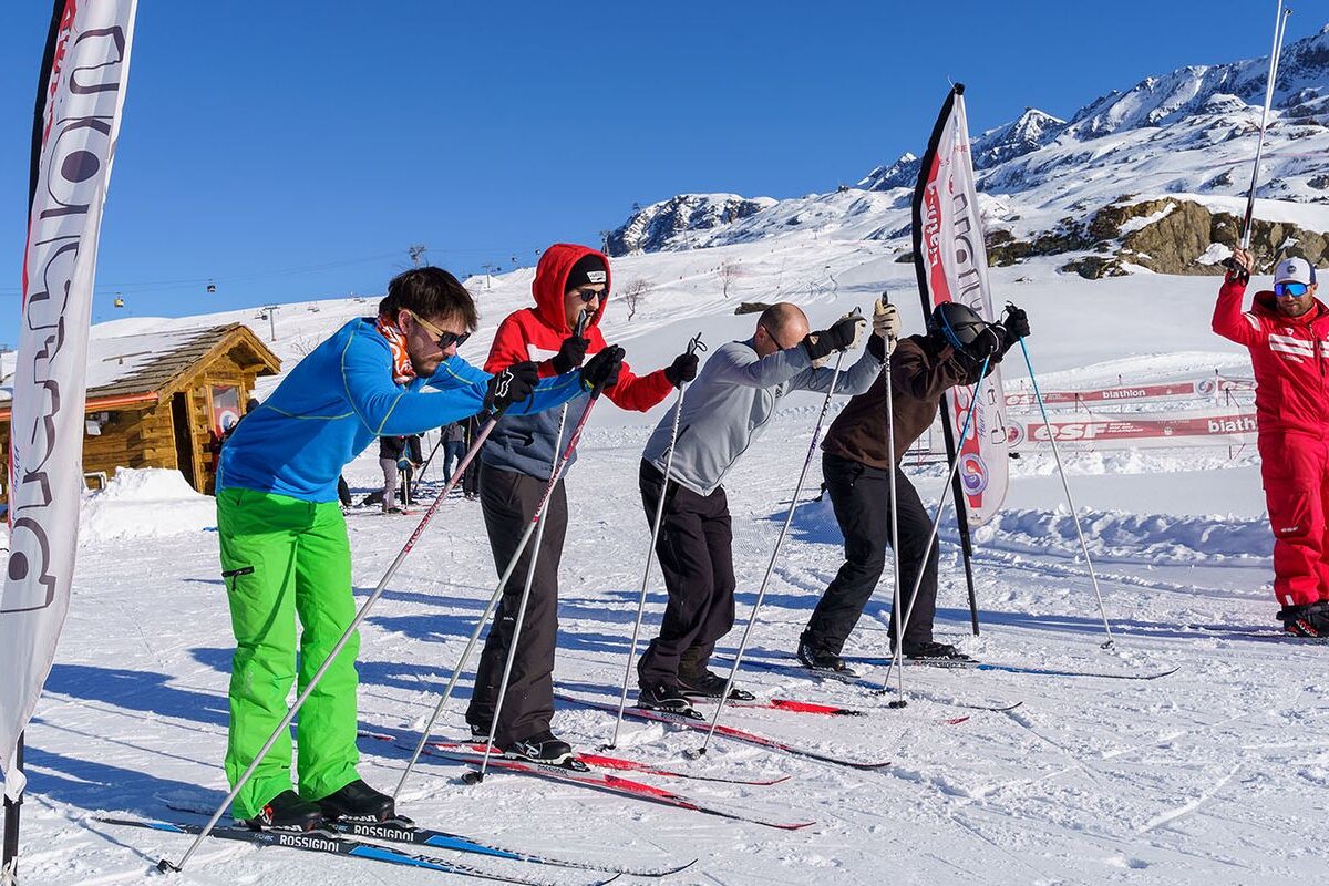 Skiers are getting ready to go down a snowy slope in front of a banner that says biatlon