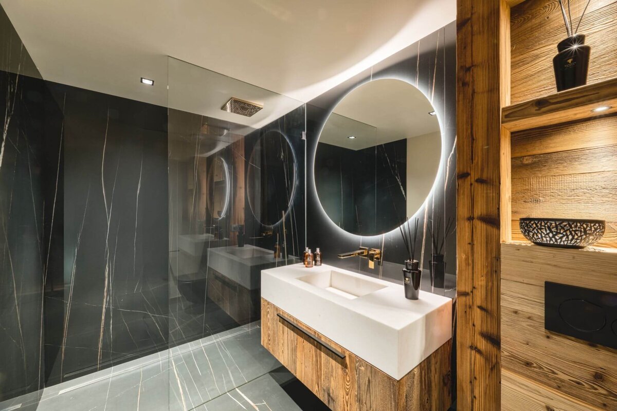 A bathroom with two sinks and a round mirror
