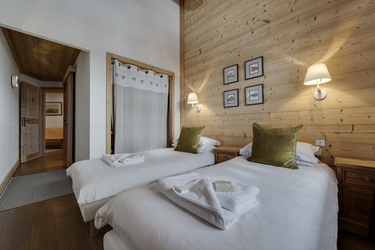 A bedroom with two beds and four pictures on the wall