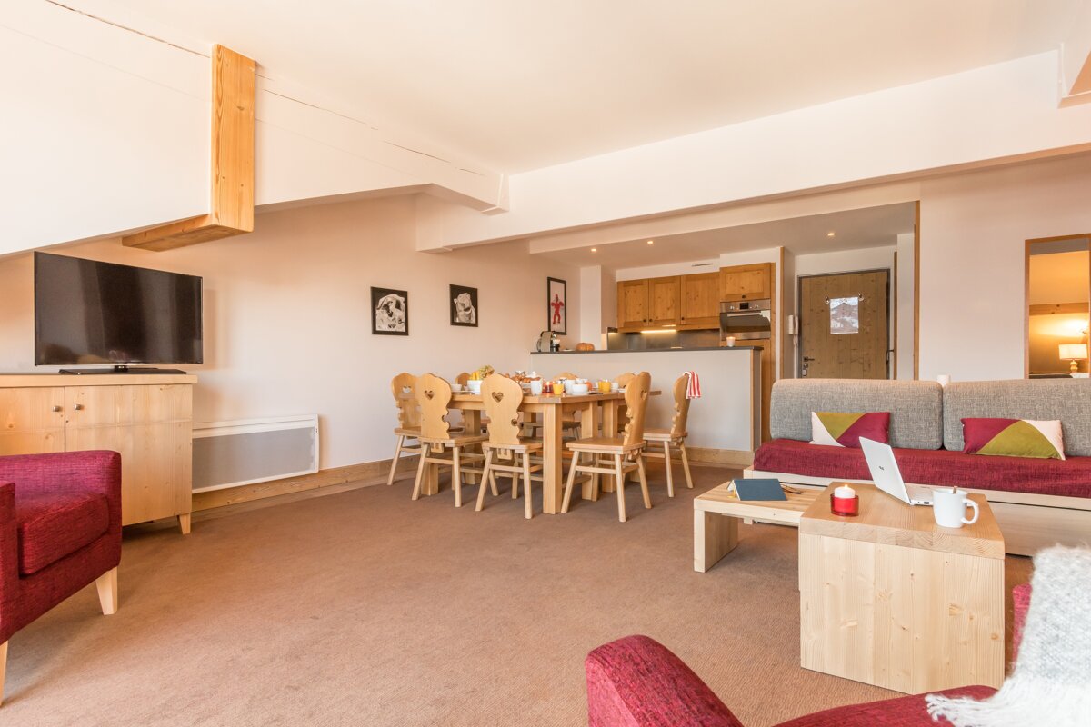 A living room with a table and chairs and a flat screen tv