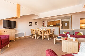 A living room with a table and chairs and a flat screen tv
