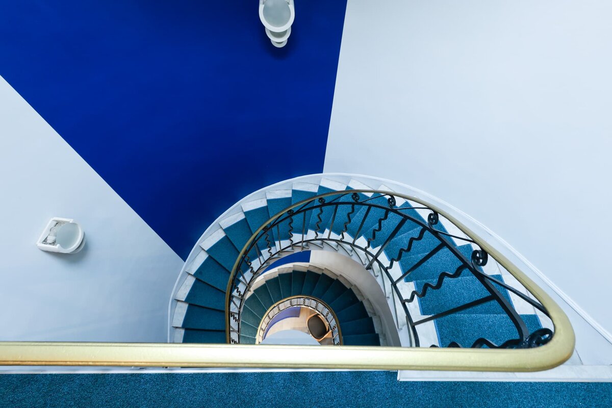 A blue and white spiral staircase with a gold railing