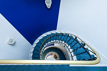 A blue and white spiral staircase with a gold railing